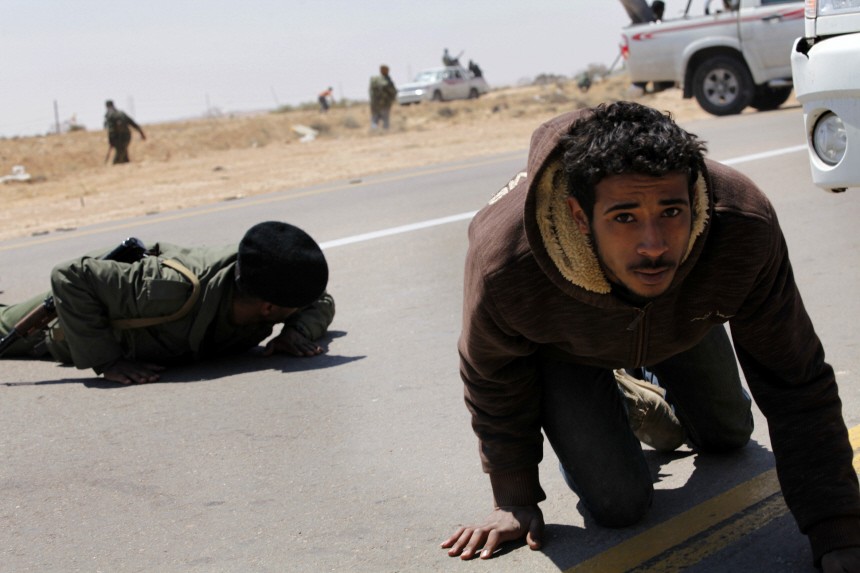 Rebels take cover from explosions during a fight with troops loyal to Muammar Gaddafi outside Brega in eastern Libya