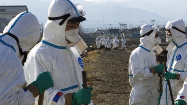 Atomkatastrophe in Japan: In weißer Strahlenschutzmontur suchen Polizisten in der Sperrzone um Fukushima-1 nach Todesopfern des Bebens.