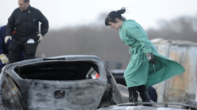 A forensic expert examines burnt cars on the motorway A 19 near eastern German village of Kavelstorf