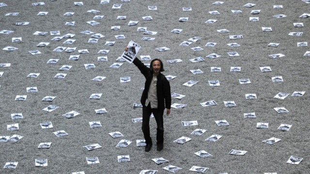 China: Nach der Festnahme von Ai Weiwei: In der Londoner Tate Modern liegen Ai Weiweis Sonnenblumenkerne. Auf der Installation finden sich Flugblätter, in denen, wie von diesem Demonstranten, China zur Freilassung des Künstlers aufgefordert wird.