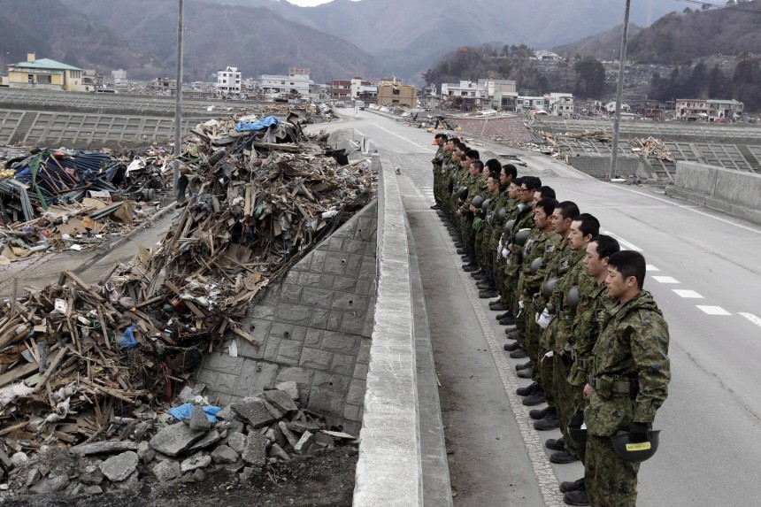 Japanese  soldiers pray for tsunami victims a month after the dis