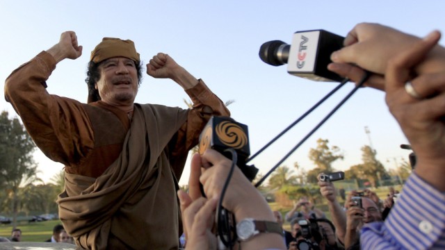 Libyan leader Muammar Gaddafi gestures, as he is surrounded by members of the media, after a meeting with a delegation of five African leaders at his Bab al-Aziziyah compound in Tripoli