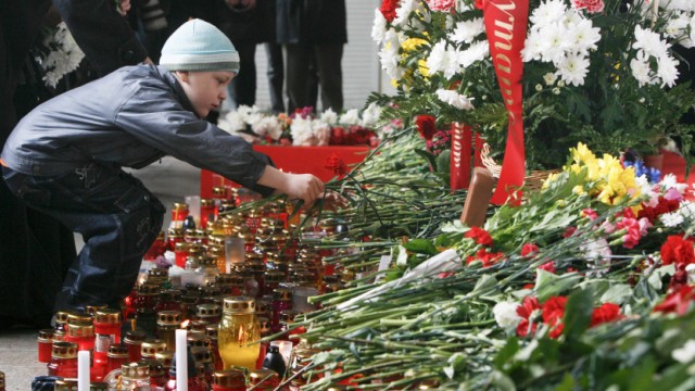 A boy places flowers at the entrance to the Oktyabrskaya metro station in Minsk