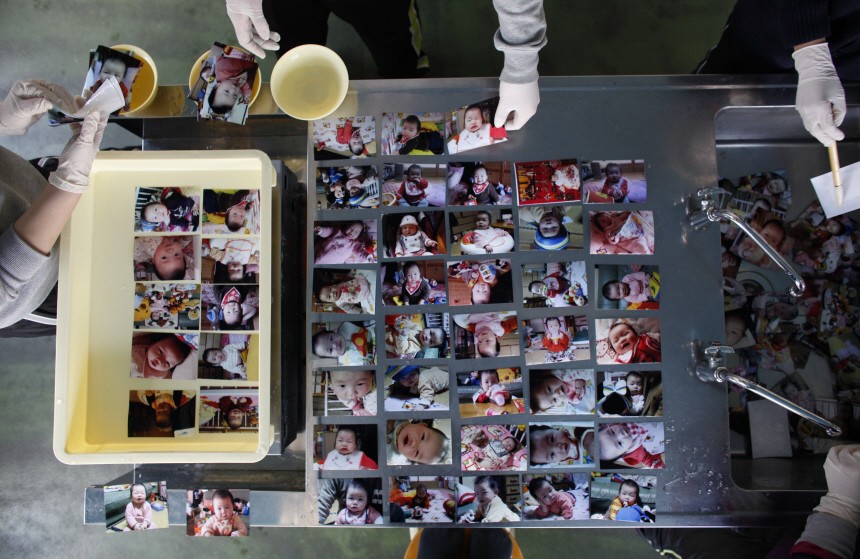 Volunteers clean baby photos that were washed by the March 11 earthquake and tsunami at a volunteer centre in Ofunato
