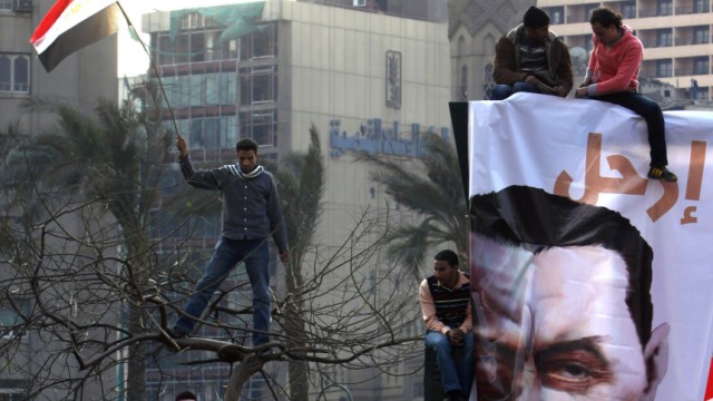 Protesters chant anti-Mubarak slogans next to a poster of Egyptian President Hosni Mubarak in Tahrir square in Cair