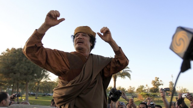 Libyan leader Muammar Gaddafi gestures, as he is surrounded by members of the media, after a meeting with a delegation of five African leaders at his Bab al-Aziziyah compound in Tripoli