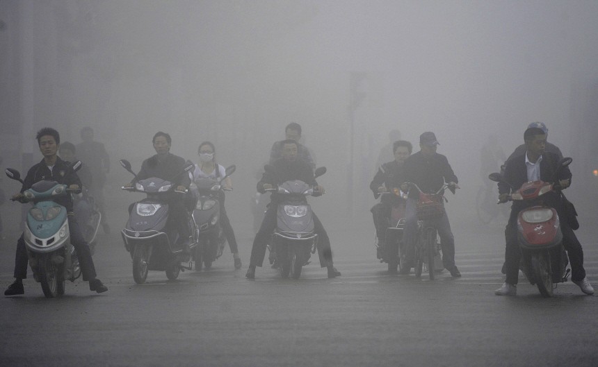 People riding scooters wait in traffic amid fog in Hefei
