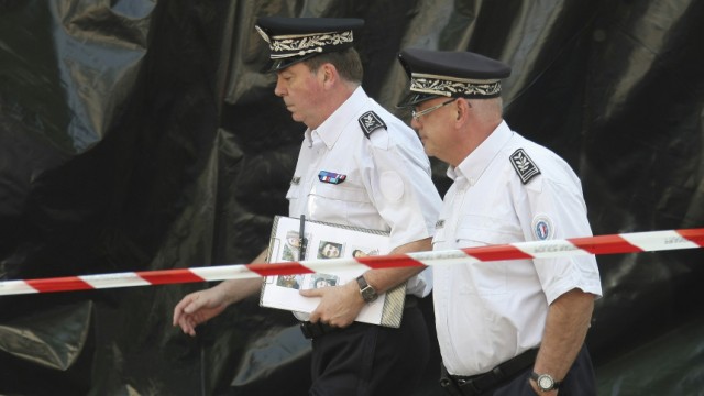 Frankreich: Französische Polizisten inspizieren den Tatort. Einer von ihnen trägt eine Akte mit den Bildern der Vermissten unter dem Arm.