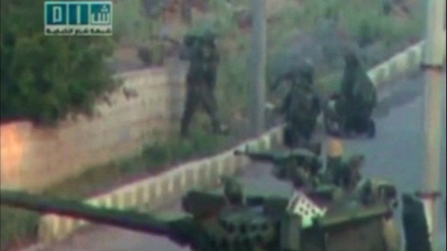 Soldiers take up position near a tank on a street in a location given as Deraa in this still image taken from amateur video