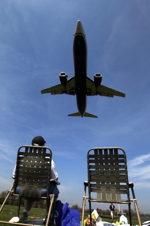 A woman sits in a lawn chair watching planes land at Ronald Reagan National Airport in Washington