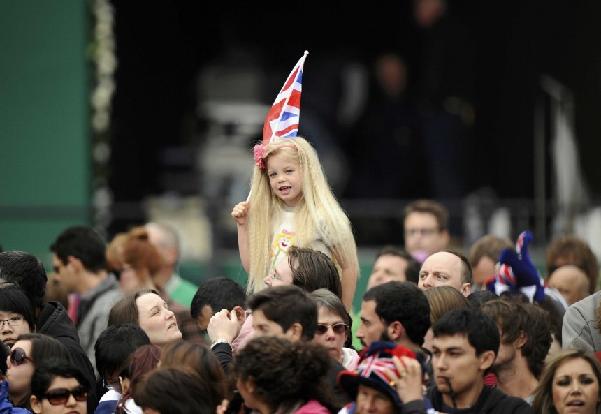 A girl with a British flag smiles among people gathered outside Buckingham Palace before the wedding of Britain's Prince William and Kate Middleton at Westminister Abbey, in central London