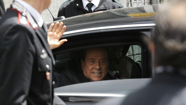 Italy's Prime Minister Silvio Berlusconi waves as he leaves the Justice Palace in Milan