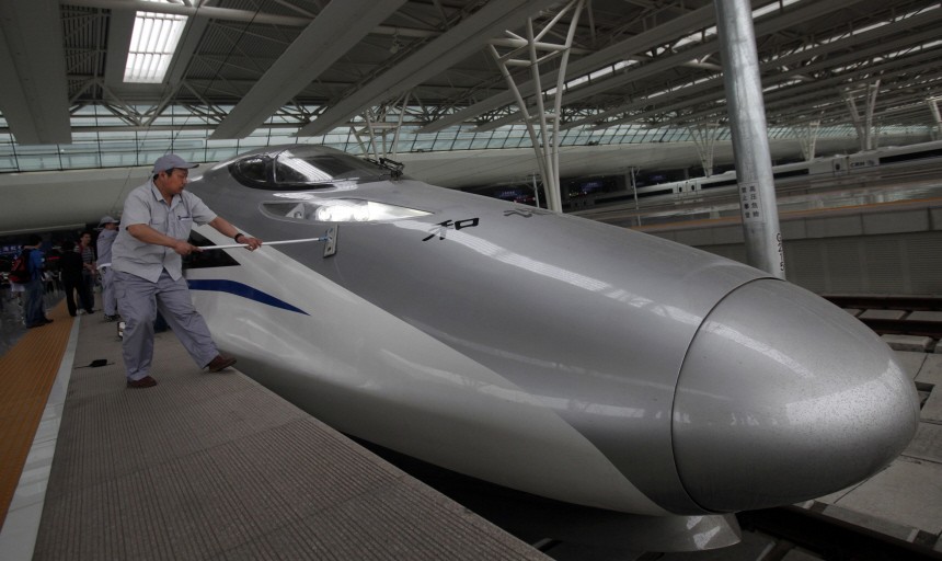 Workers clean the exterior of a bullet train serving the newly built high-speed railway between Shanghai and Beijing during its debut test at the Hongqiao Railway Station in Shanghai