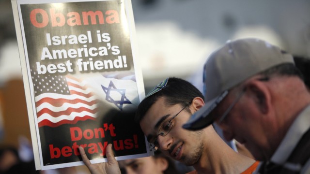 An Israeli holds a sign during a protest in front of the U.S. embassy in Tel Aviv