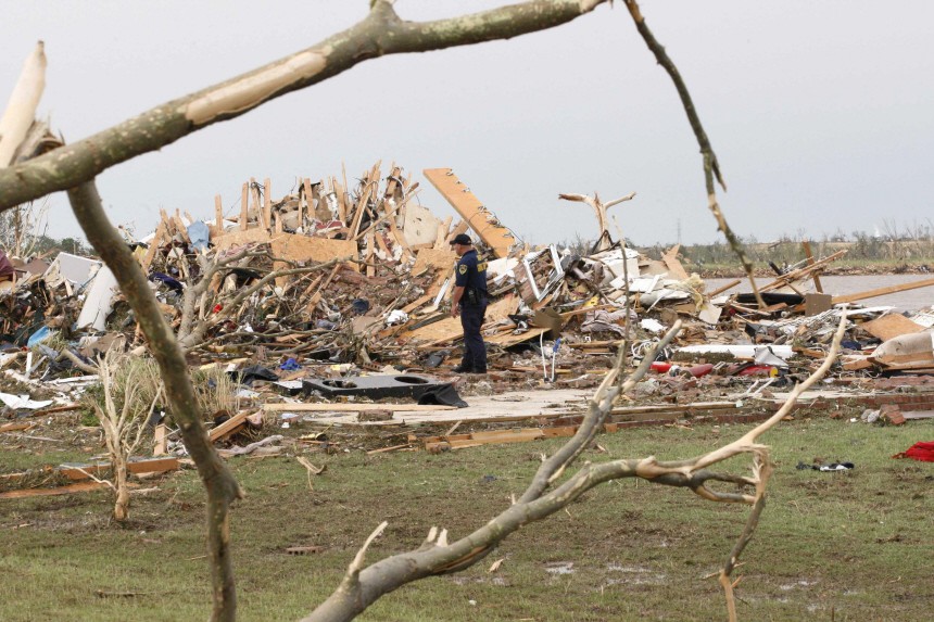 A police officer looks over a home after a tornado ripped through the Falcon Lake area of Piedmont