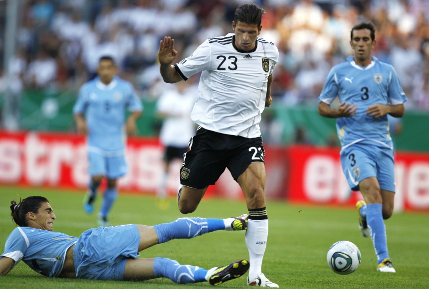 Mario Gomez of Germany challenges Martin Caceres of Uruguay during their international friendly soccer match in Sinsheim