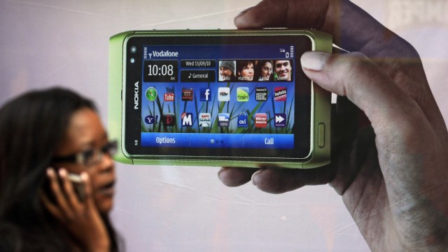 File picture of a shopper talking on a mobile phone passing an advert for the new Nokia N8 on Oxford Street in London