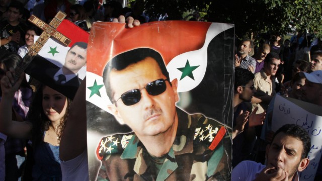 A pro-Syrian President Bashar al-Assad supporter, who rallied to a Facebook call to sit-in to support the army at Arnous square, carries his picture in Damascus
