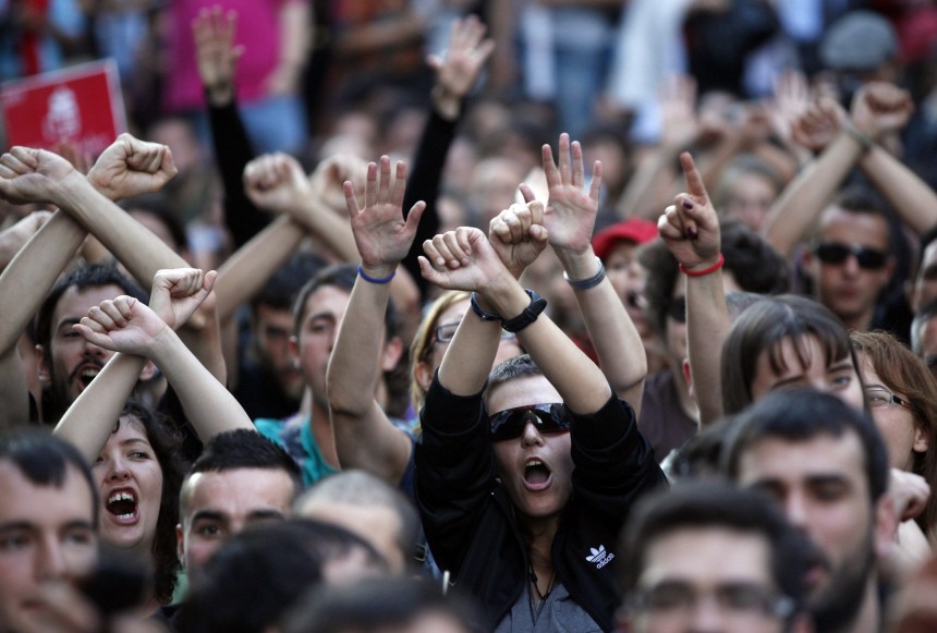 Demonstrators who have been staging a protest in Madrid's Puerta del Sol since March 15 raise their arms in front of Spain's parliament
