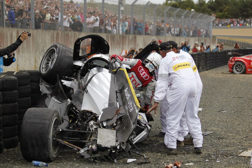 Safety crew members help Britain's Mcnish after he crashed with his Audi R18 TDI during the Le Mans 24-hour sportscar race in Le Mans