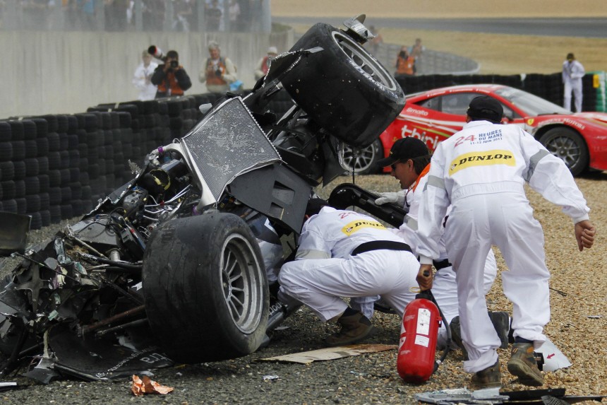 Safety crew members help Britain's McNish after he crashed with his Audi R18 TDI during the Le Mans 24-hour sportscar race