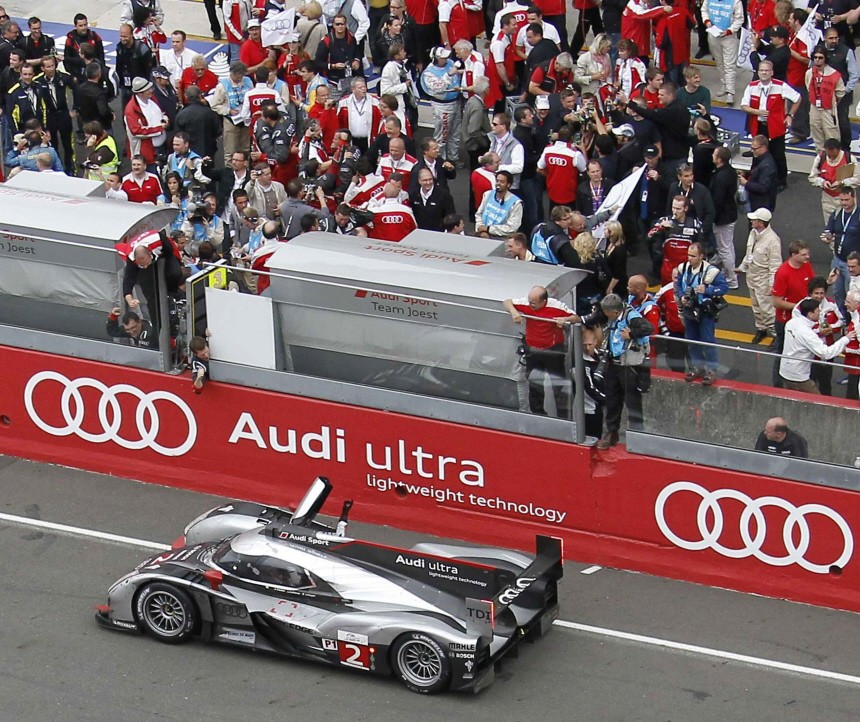 Members of Audi firm celebrate as Lotterer of Germany drives the Audi R18 TDI number 2 across the finish line at the Le Mans 24-hour sportscar race in Le Mans