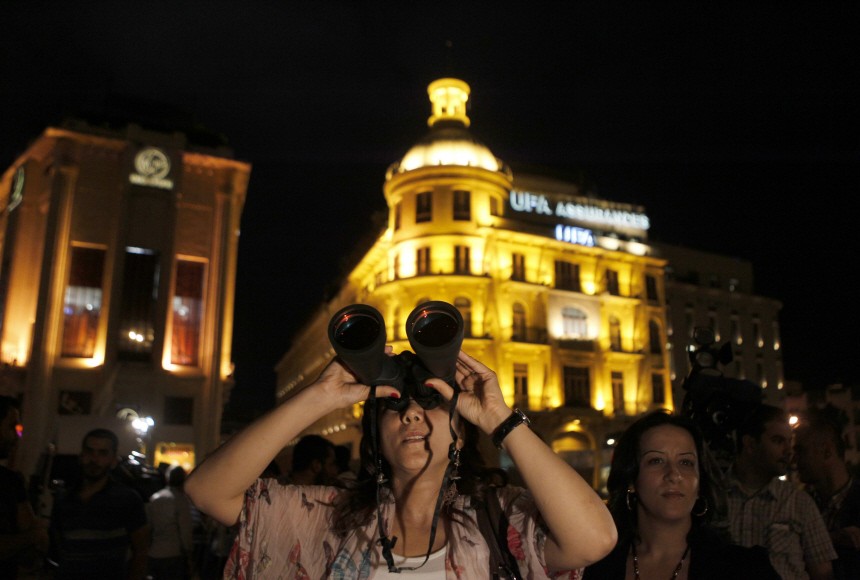 A woman uses a pair of binoculars to look at the moon during a lunar eclipse, in Beirut