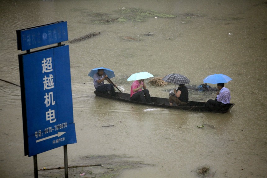 A man paddles a boat carrying local residents through a flooded area in Moshan Cun