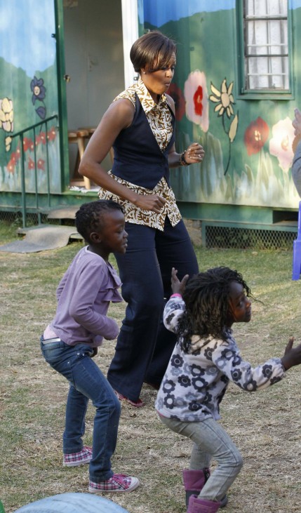 U.S. first lady Michelle Obama dances with children as she visits the Emthonjeni Community Center in Zandspruit Township, Johannesburg