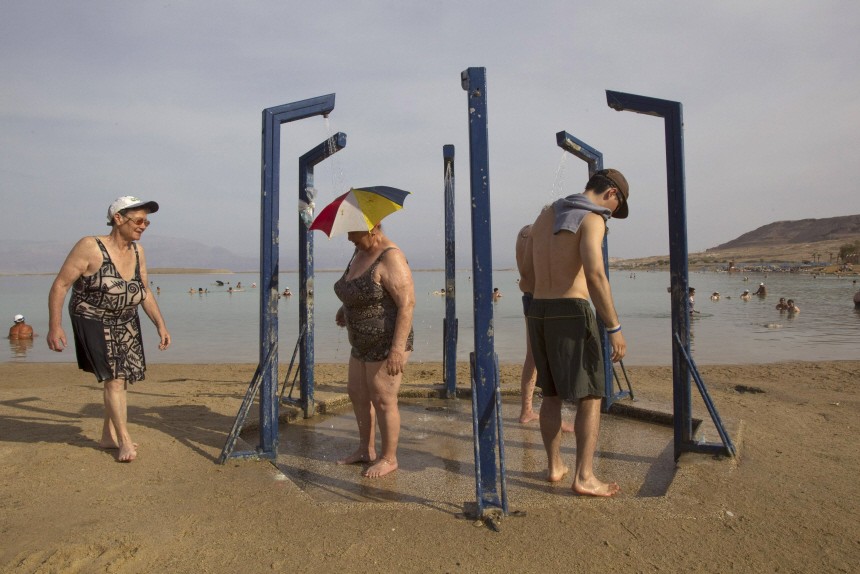 Tourists take a shower after bathing in the Dead Sea resort of Ein Bokeq