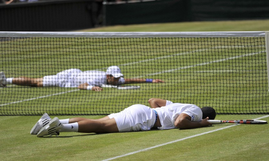 Novak Djokovic of Serbia and Jo-Wilfried Tsonga of France both lay on the ground after falling as they dived to hit returns during their semi-final match at the Wimbledon tennis championships in London
