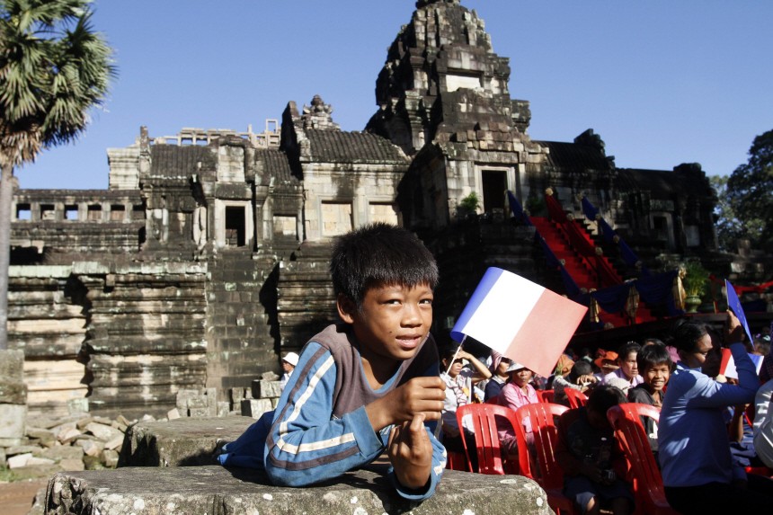 A boy holds a French flag during the inauguration ceremony of the Baphuon temple in Siem Reap