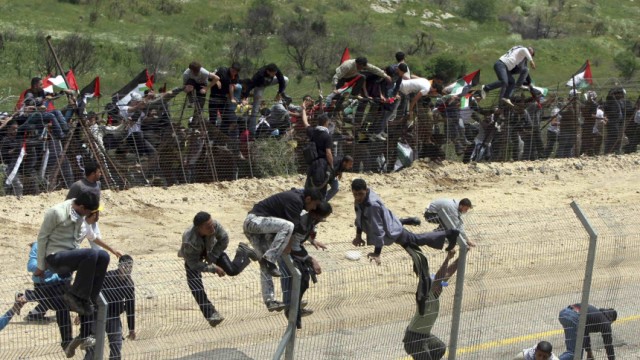 Syrian protesters climb the border fence between Syria and Israel during a demonstration marking 'Nakba' near Majdal  Shams