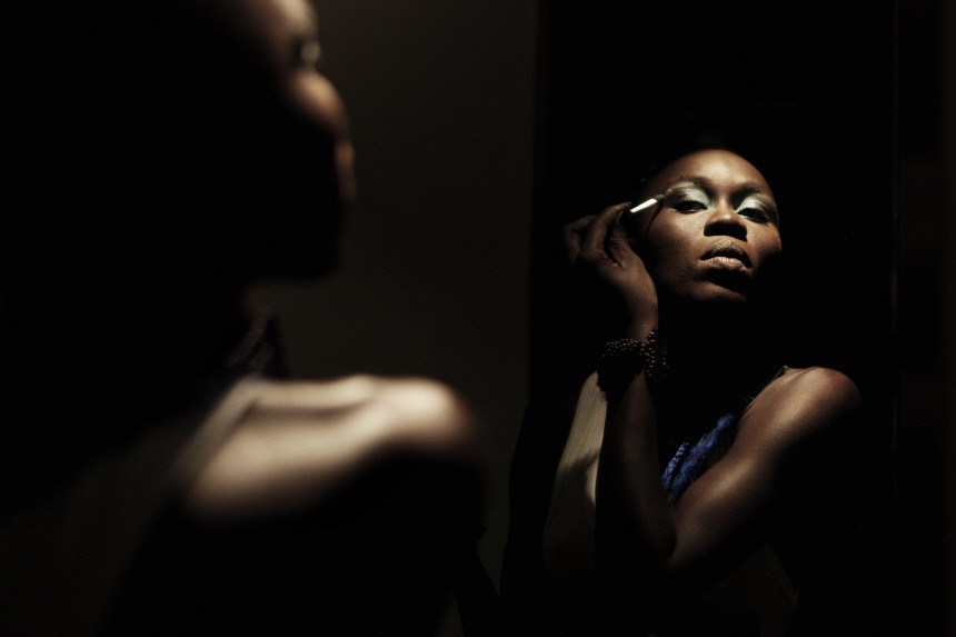 Senegalese model Dieng applies make-up in bathroom mirror backstage before show during Dakar Fashion Week in Senegal's capital