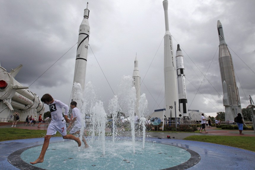 Youths run through the water fountain in the Rocket Garden of Kennedy Space Center Visitor Complex near Cape Canaveral