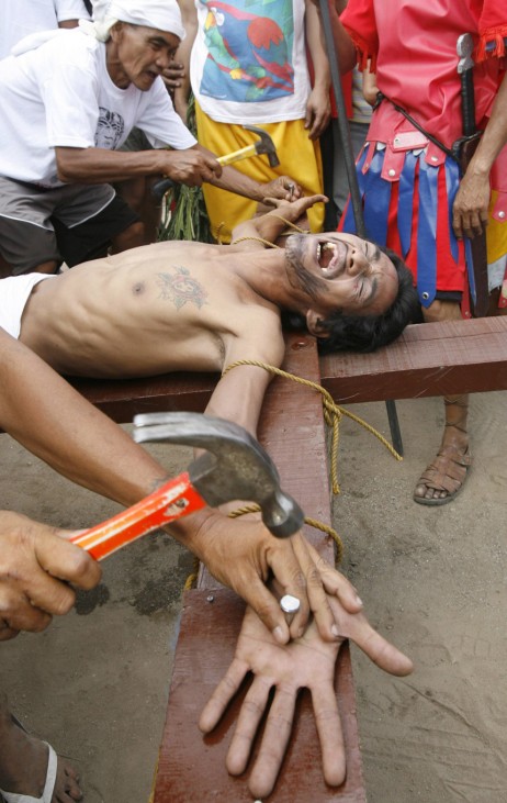 A penitent reacts as he is nailed to a wooden cross in Pampanga province