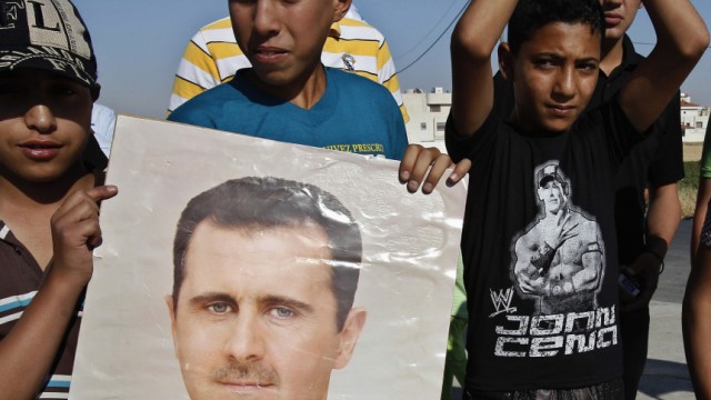 A poster of Syria's President Assad is held up as Syrians living in Jordan shout slogans during a demonstration in support of Assad in front of the Syrian embassy in Amman
