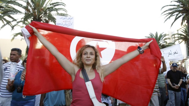 A woman holds up a Tunisian flag during a demonstration in Tunis