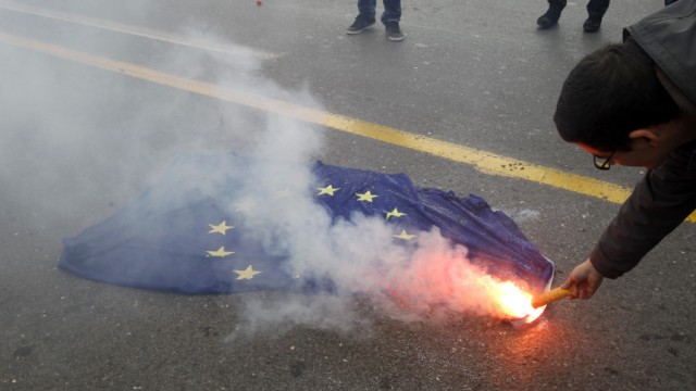 Youth supporting Greek Communist party sets fire to EU flag during rally against attacks on Libya's leader Gaddafi's air defences by Western-led forces, in Athens