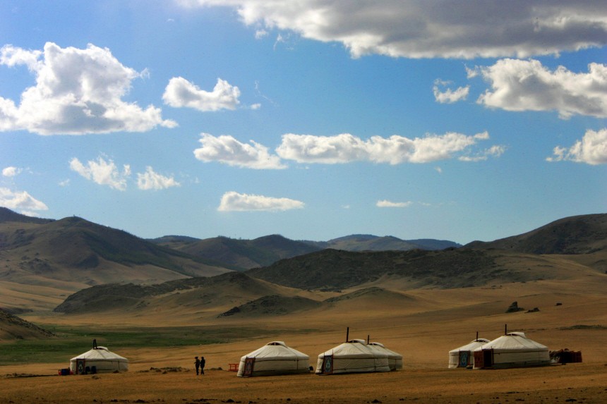 Mongolian nomads walk outside their traditional tent homes near Kharkorin