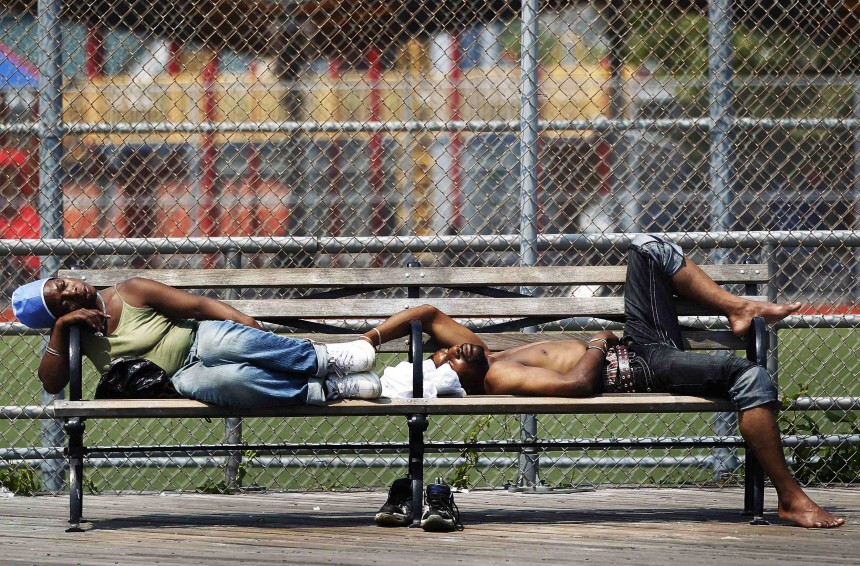 People sleep on a bench along the boardwalk at Coney Island in the Brooklyn borough of New York