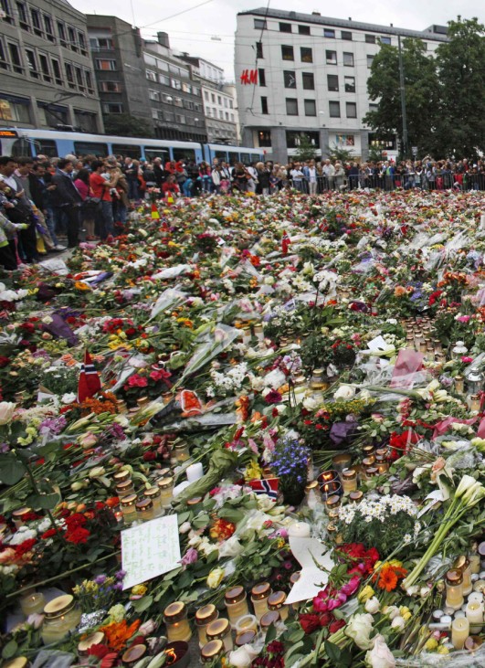 People mourn around a sea of flowers placed in memory of those killed in Friday's bomb and shooting attack in front of Oslo Cathedral