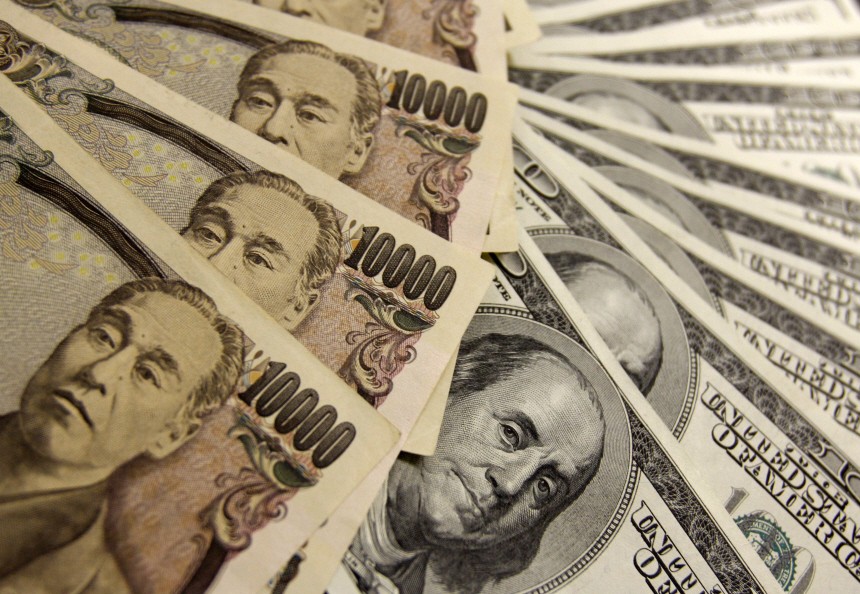 Japanese yen notes are piled atop U.S. dollar bills during a photo opportunity at an office of Interbank Inc. money exchange in Tokyo
