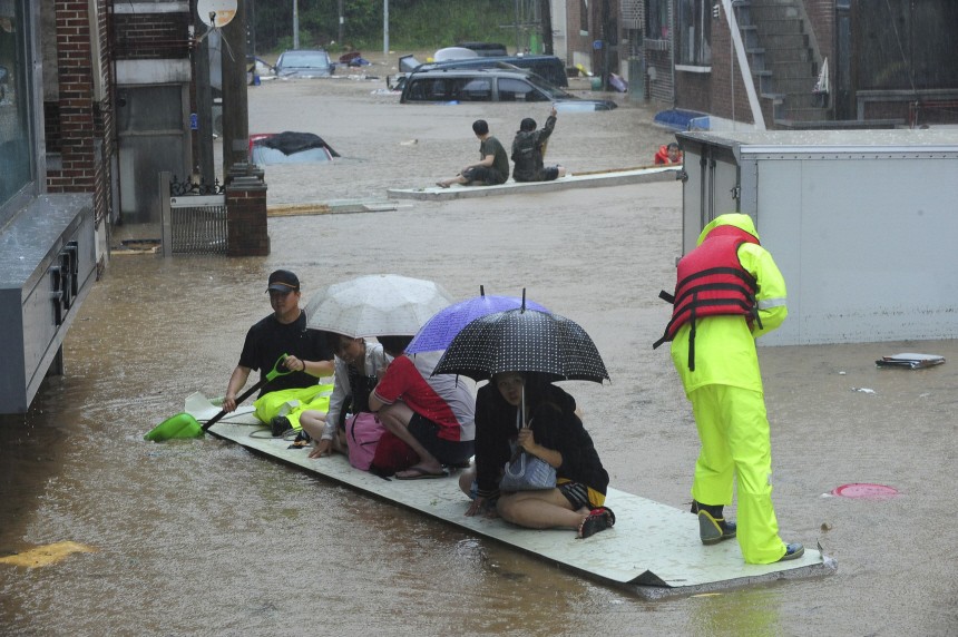 Residents travel on part of a polystyrene wall move to escape floodwaters after a river burst its banks following heavy rains in Gwangju