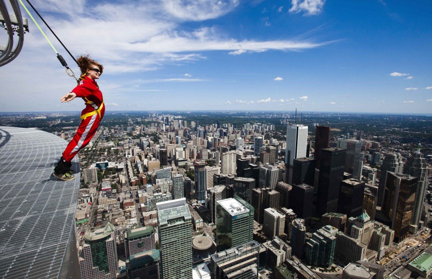A reporter leans over the edge of the catwalk during the media preview for the 'EdgeWalk' on the CN Tower in Toronto