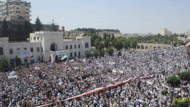 A giant Syrian flag is held by the crowd during a protest against President Bashar al-Assad after Friday prayers in the city centre of Hama