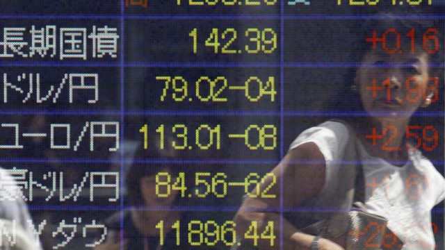 A woman is reflected on a board displaying the current Japanese yen's exchange rate against the U.S. dollar outside a brokerage in Tokyo
