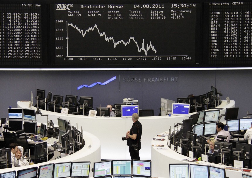 A photographer waits to take a picture in front of the DAX board at the Frankfurt stock exchange