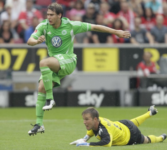 VFL Wolfsburg's Helmes jumps over FC Cologne goalkeeper Rensing after scoring a goal in their German first division Bundesliga in Cologne