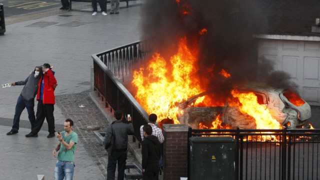 Ausschreitungen in England: Ein Foto fürs Familienalbum: Bürger Birminghams vor einem brennenden Auto.